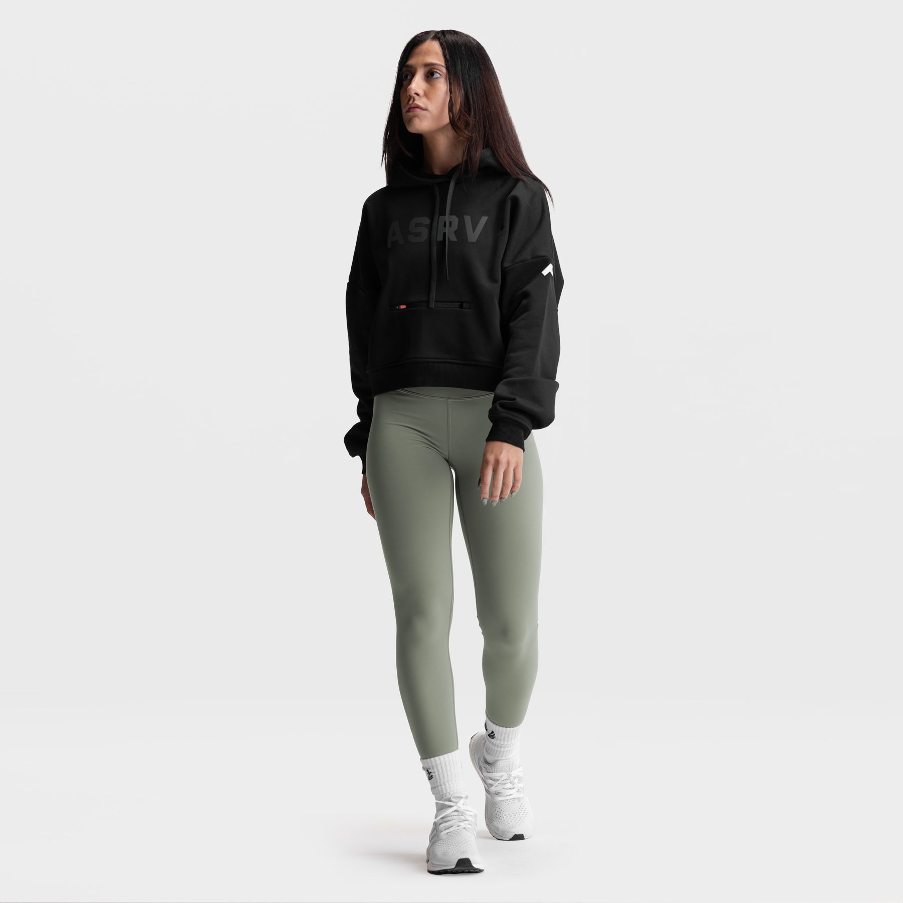Black cropped hoodie and sage green leggings worn by model, front view