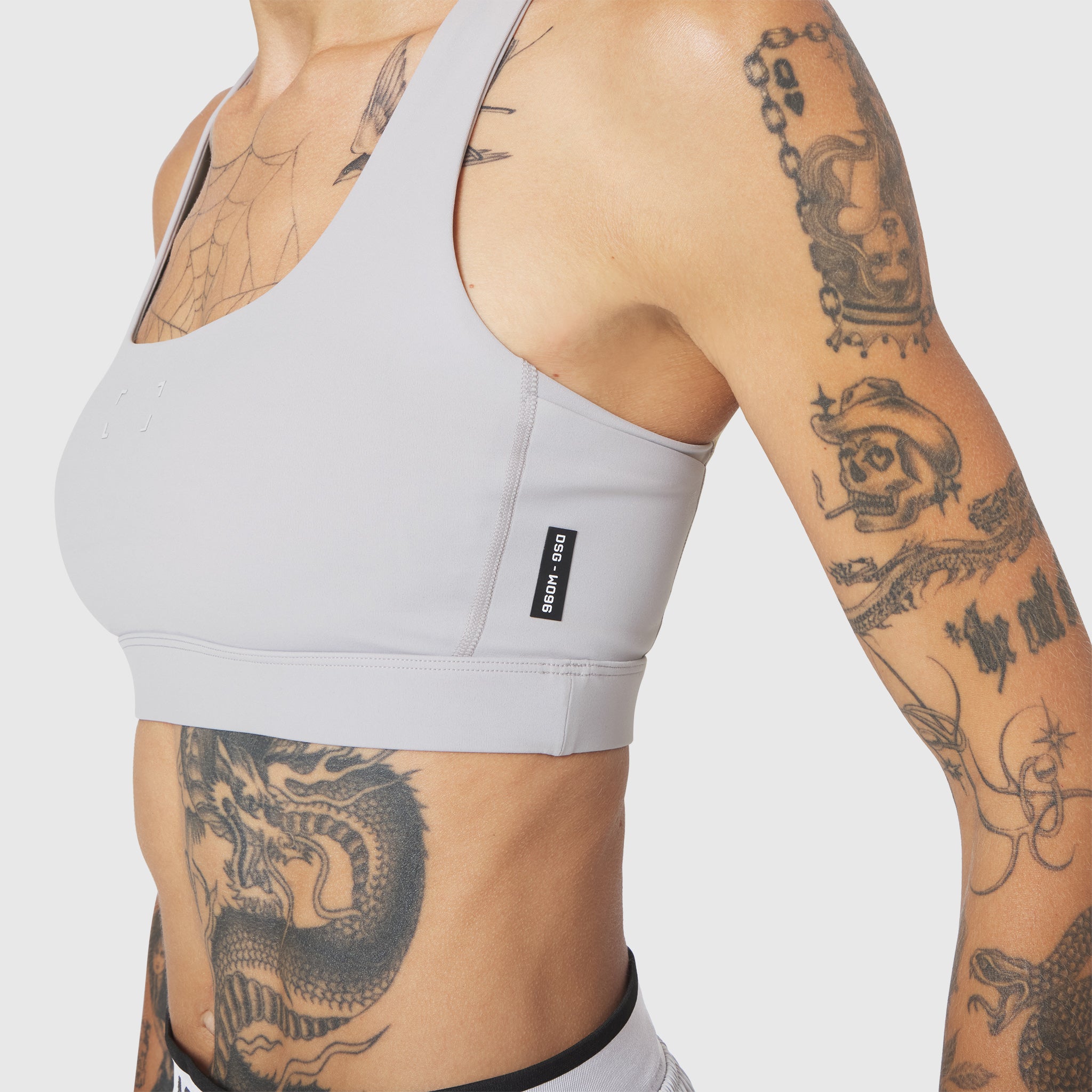 W096 LYCRA® ADAPTIV Racerback Sports Bra in Slate Grey, worn by model with tattoos, side view