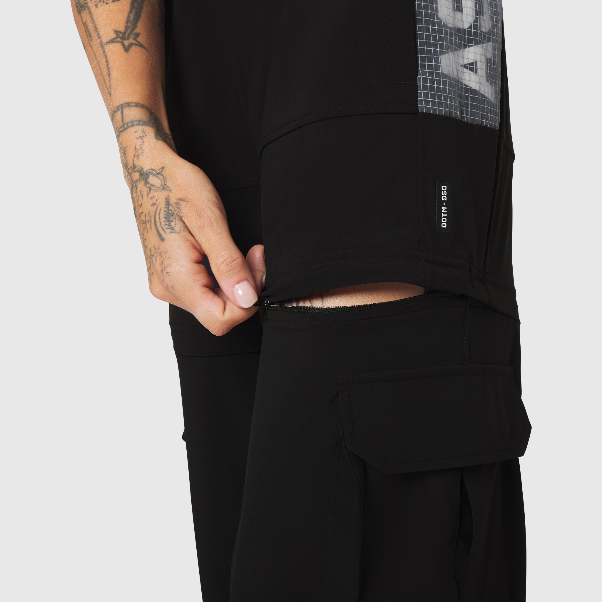 W100 2-in-1 Convertible Pant in black, worn by model showing zippered cargo pocket detail