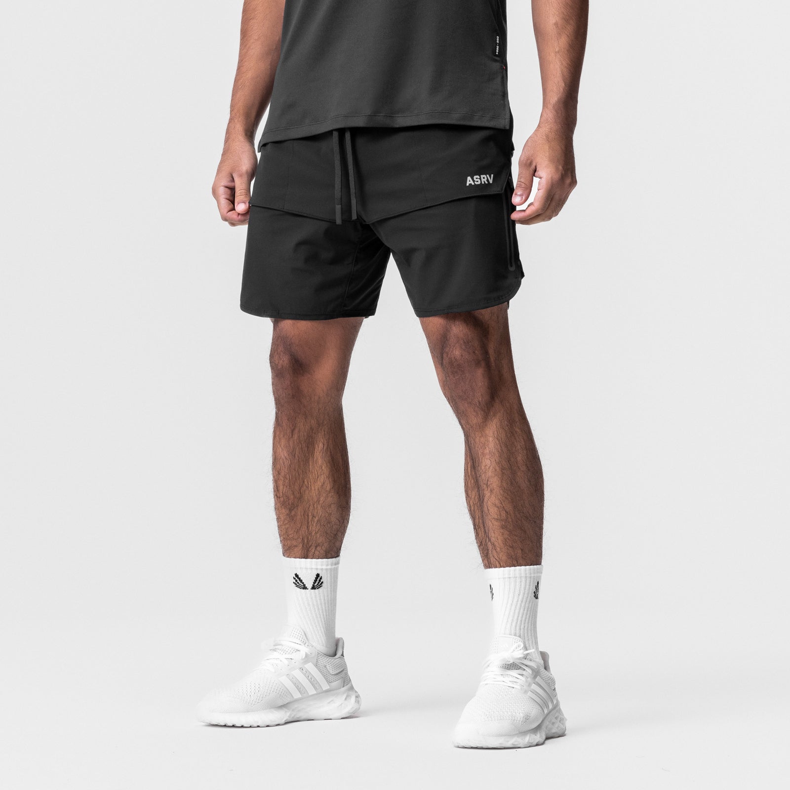 ASRV Tetra-Lite Tech Short in black, modeled with white socks and sneakers, front view