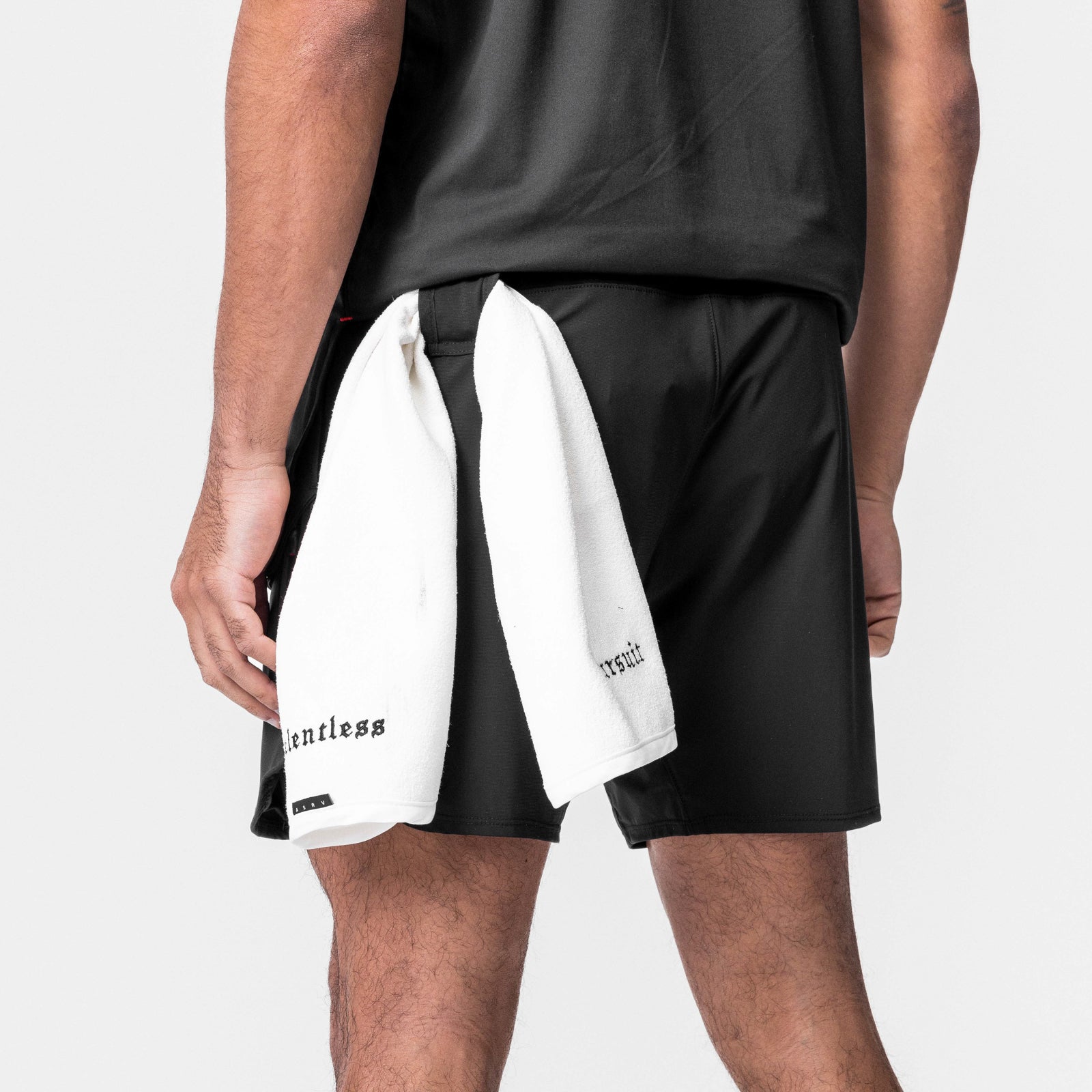 Black Tetra-Lite 7" Tech Shorts worn by model with white towel over shoulder, back view