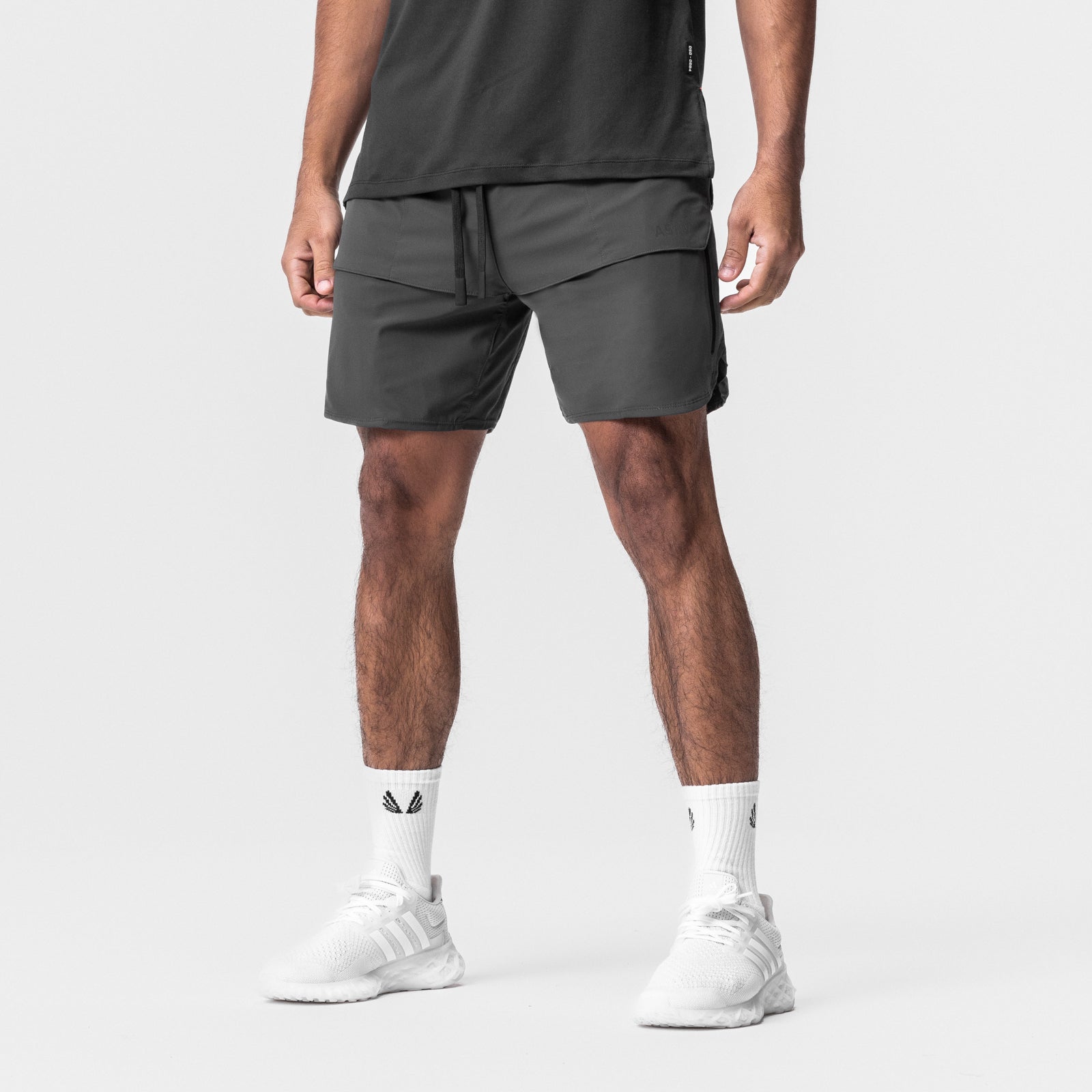 Tetra-Lite Tech Short in space grey, modeled with white socks and sneakers, front view