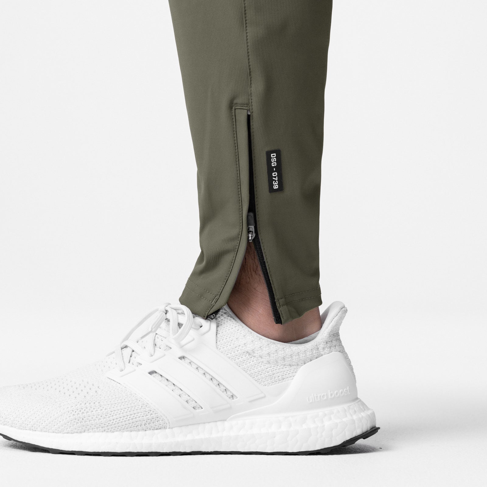 All Condition Moto Jogger in olive worn with white sneakers, leg detail showing ankle zip