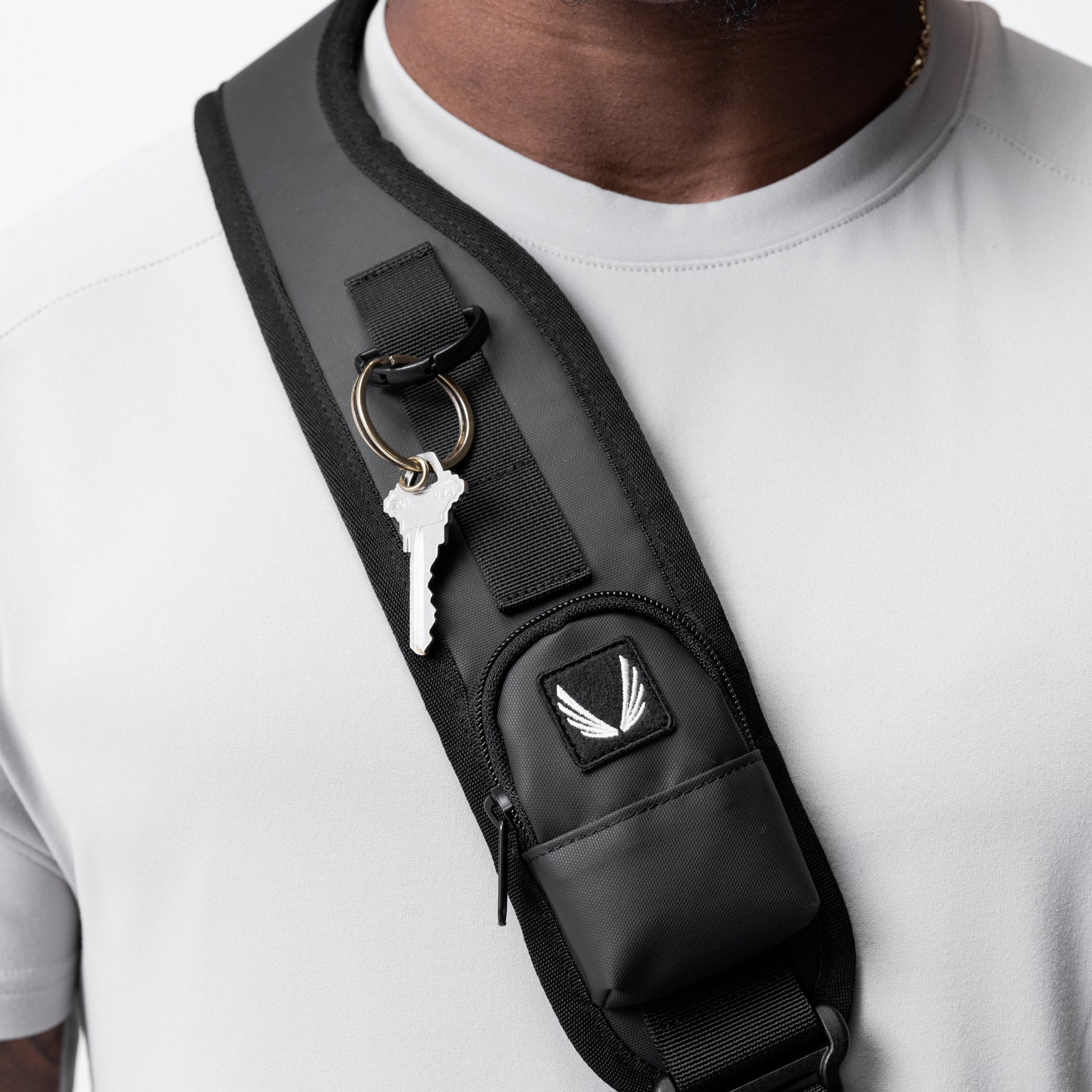 Waterproof holster sling bag in black worn across chest on model, with key attached to strap