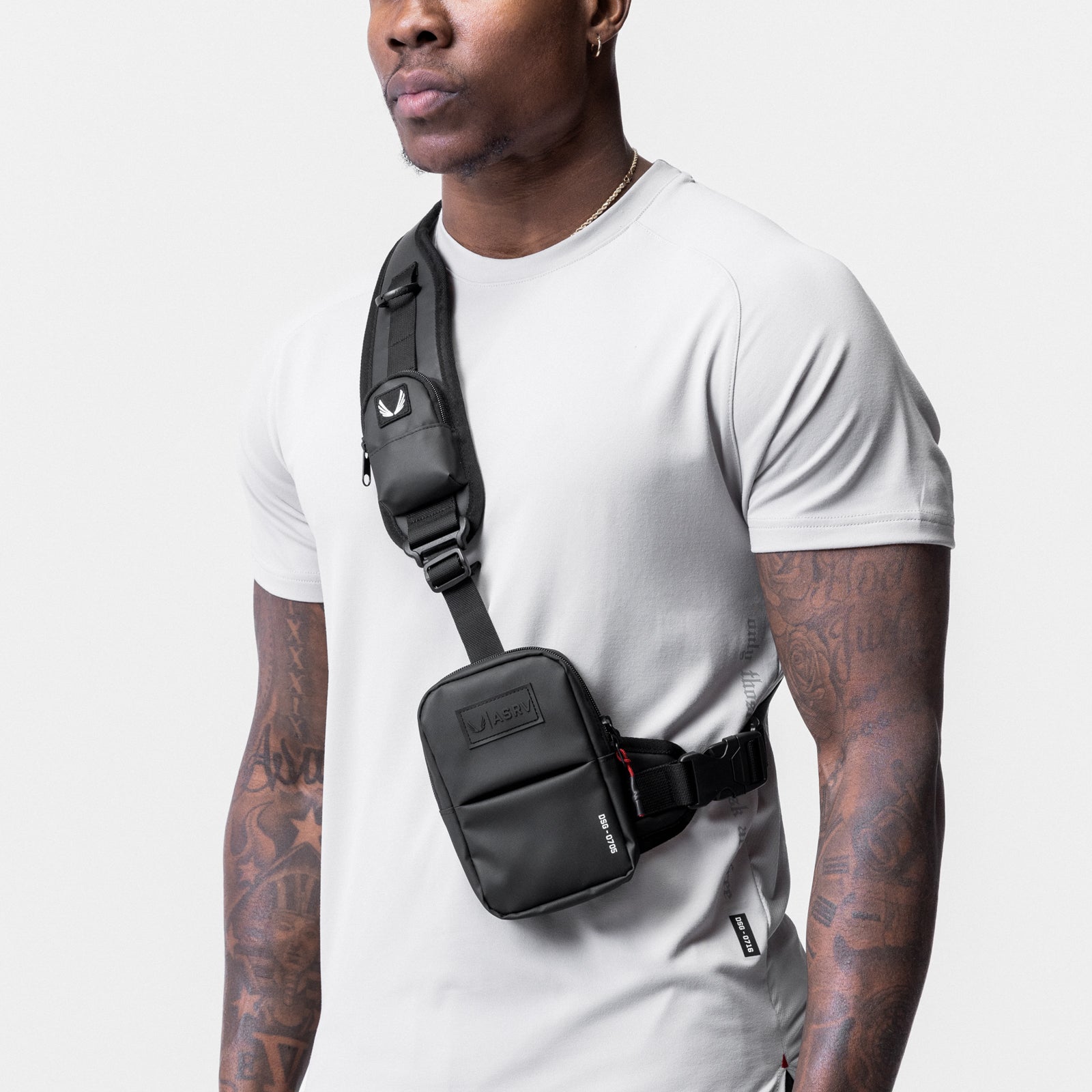 Waterproof holster sling bag in black, worn across chest on model in white tee