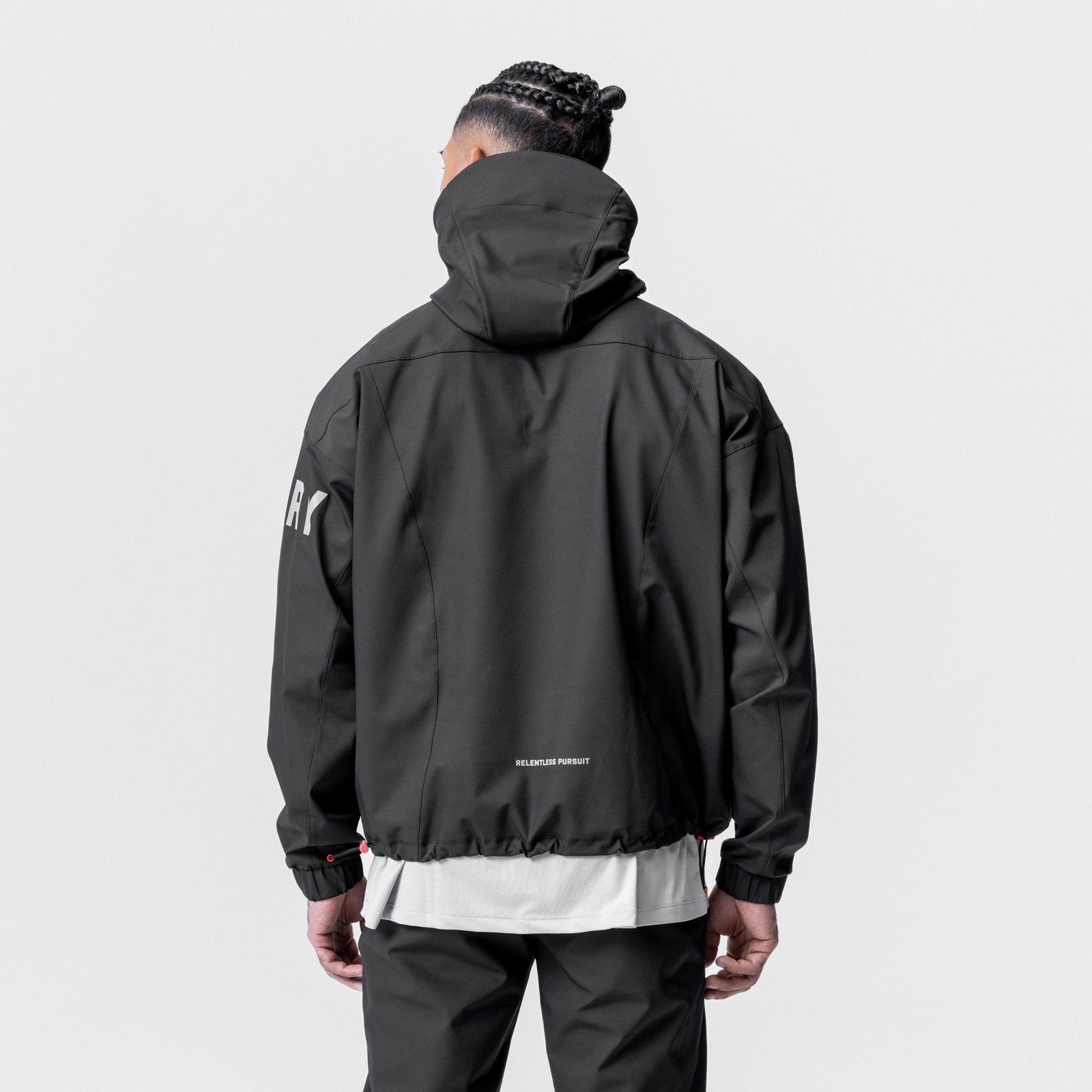 Black weather-ready anorak jacket worn by model, back view, with white stripe detail