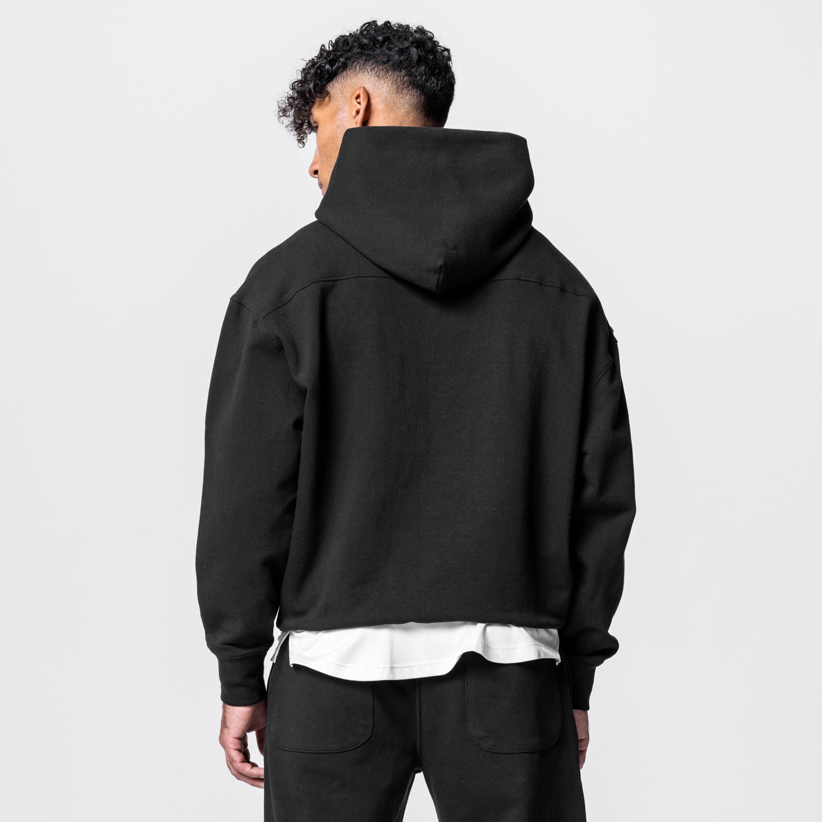 Black Tech-Terry™ Hoodie worn by model, back view, with white undershirt visible