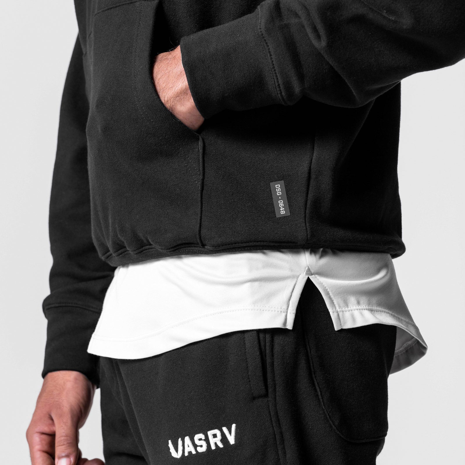 Black Tech-Terry Hoodie worn by model, layered with white shirt, showing front pocket and VASRV branding