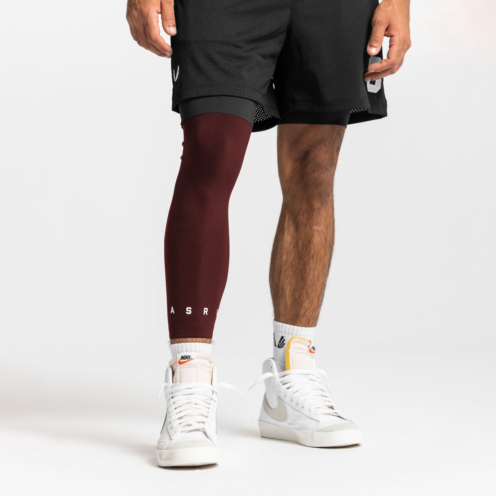 WarpFlexx® Leg Sleeve in crimson worn on model's left leg with black shorts and white sneakers