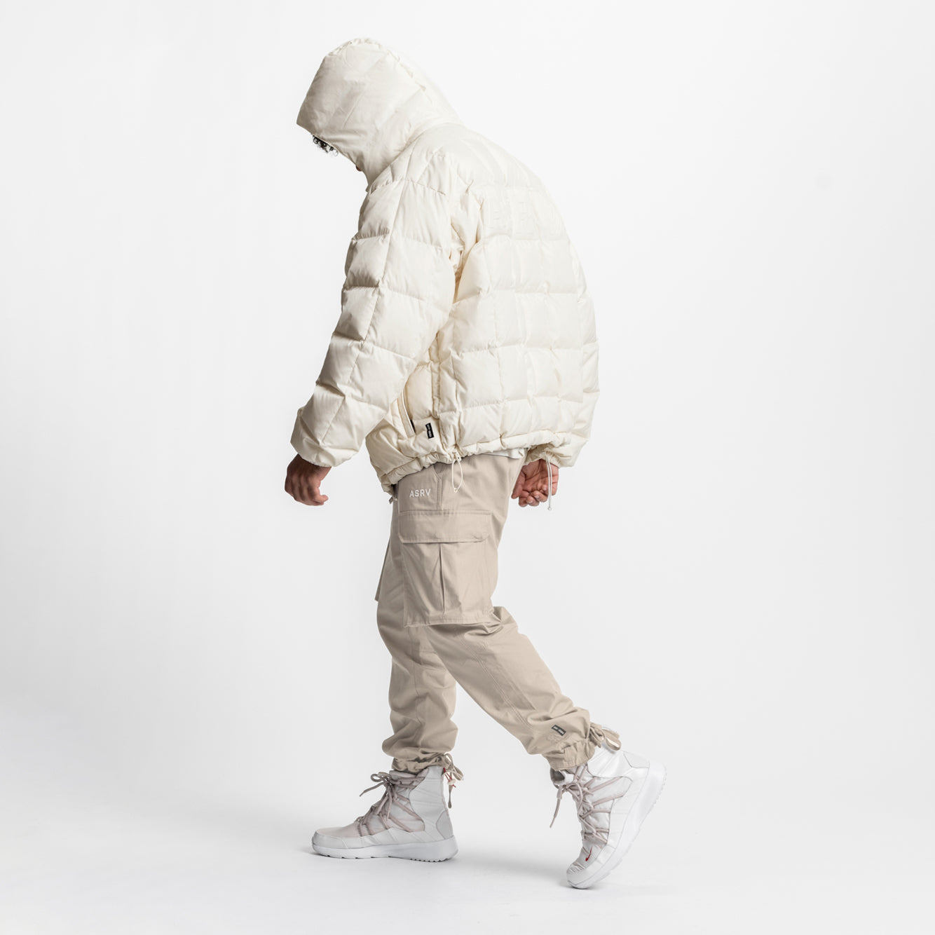 Ivory cream down puffer jacket worn by model in side profile stance with matching cargo pants