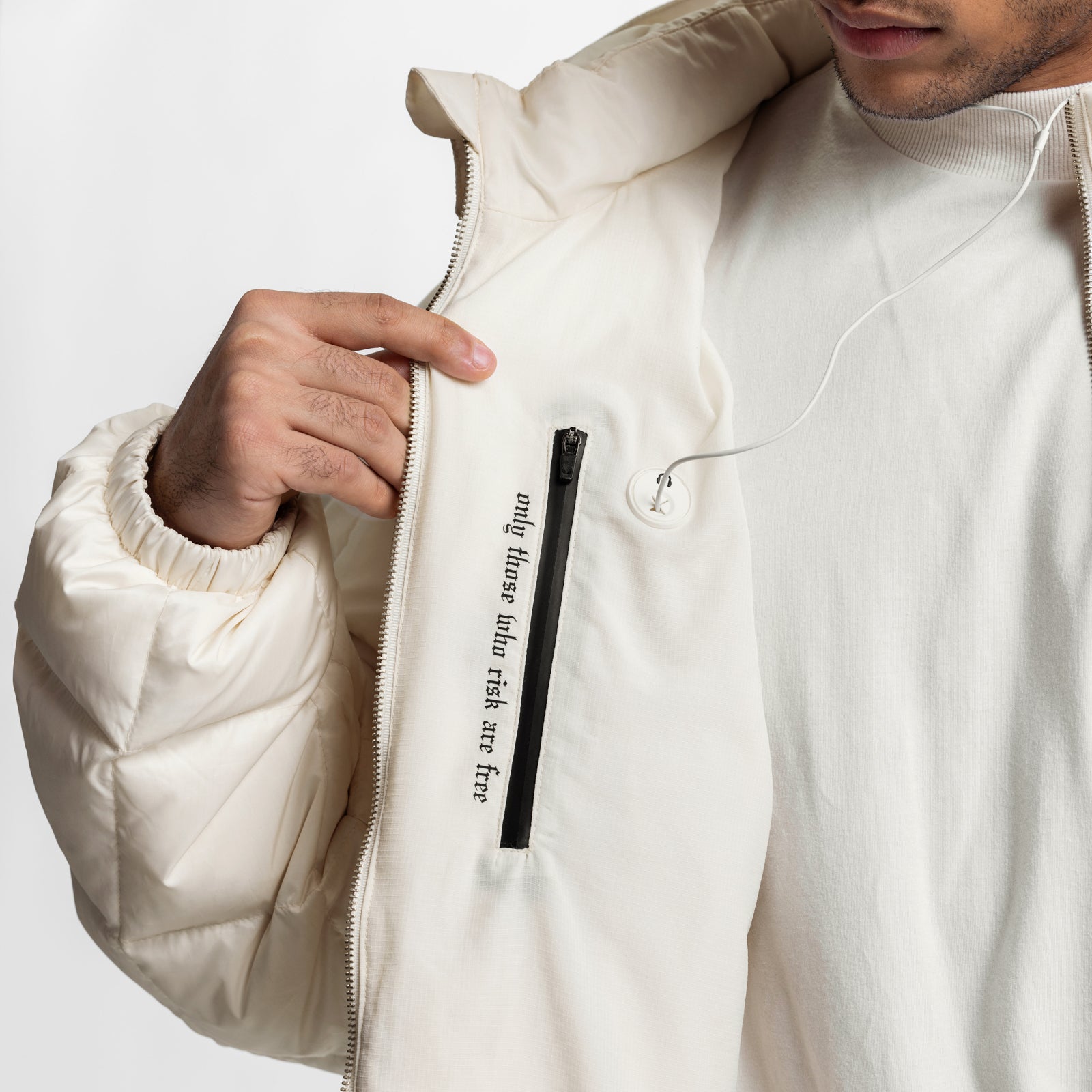 Weather-Ready Down Puffer Jacket in ivory cream, modeled with hand opening zipper and earbuds visible